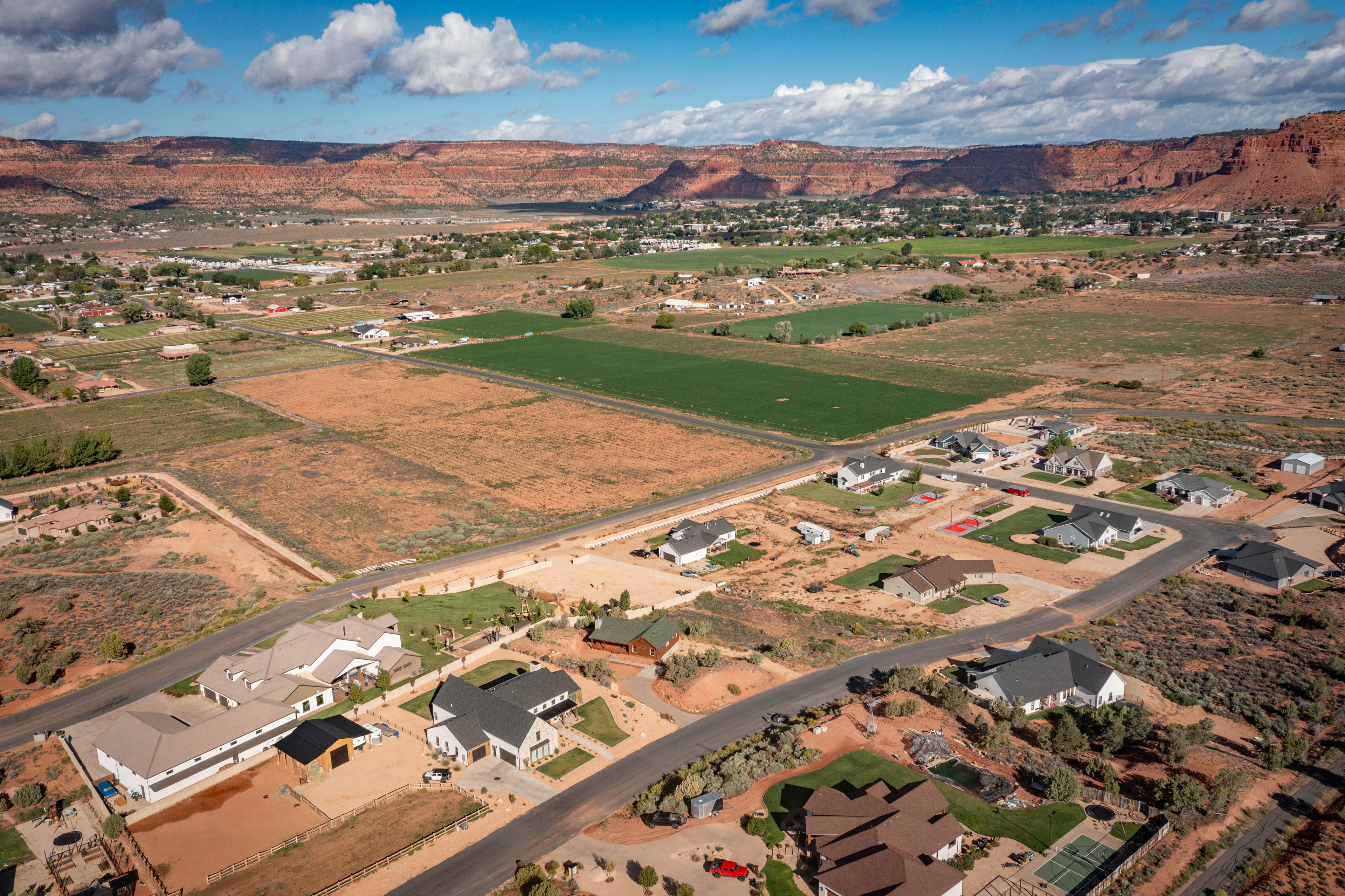 Wide aerial of Kanab with red rock cliffs and residential development — Southern Utah